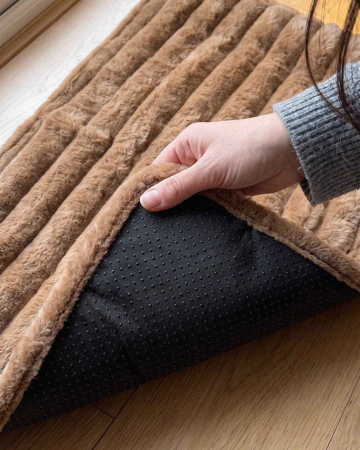 Hand lifting a corner of the mat to show the dotted non-slip base